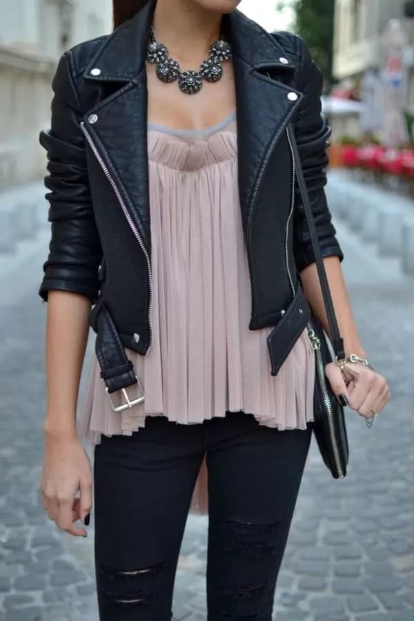 chaqueta negra complementada con un collar vintage, camisa rosada holgada y jeans negros desgatados