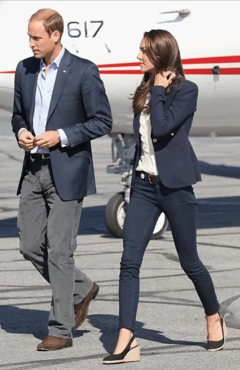 Kate Middleton blazer azul marino con botones dorados sobre una blusa estilo delantal y jeans