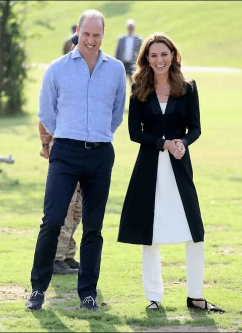 Kate Middleton abrigo negro con botones ciñen el torso y pantalón blanco